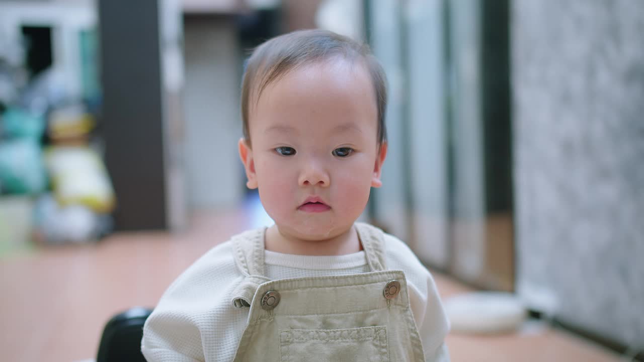 一个蹒跚学步的孩子面带微笑地看着镜头，嘴里吐着口水视频素材