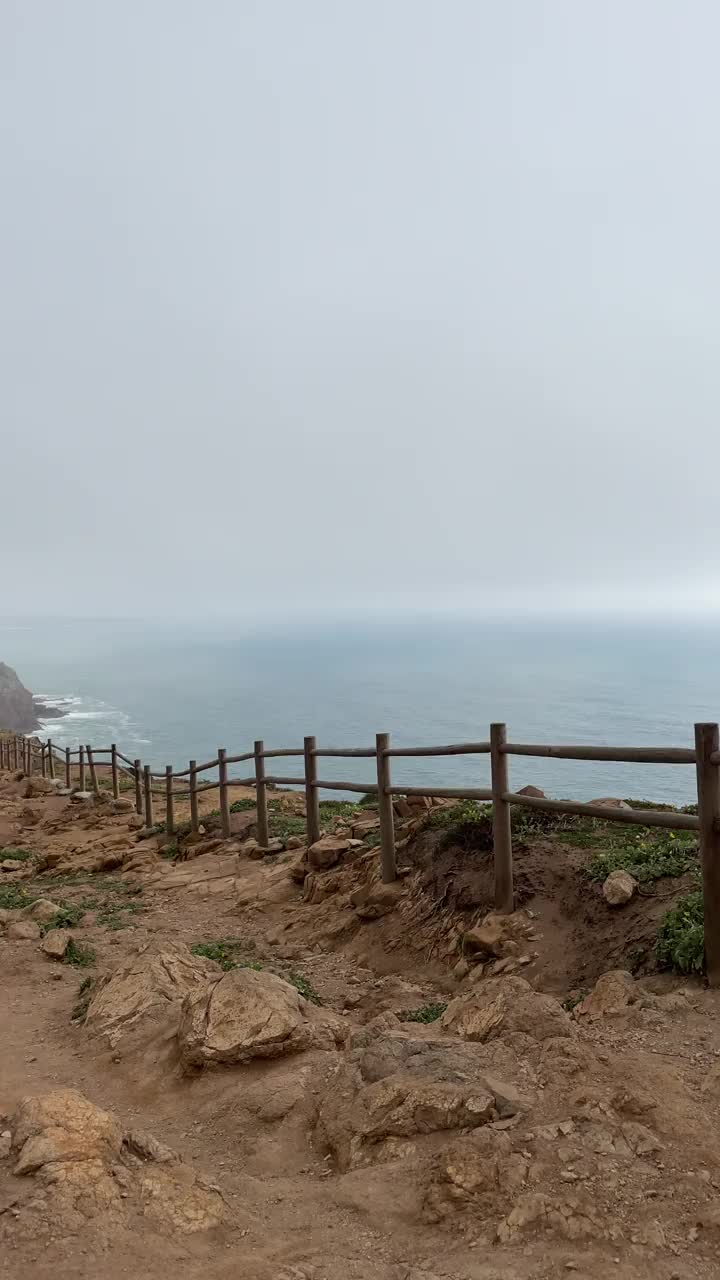 一名妇女走过海滨小路上的木栅栏视频素材