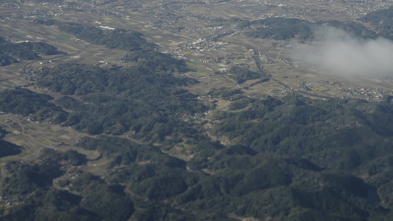 美丽的鸟瞰图在陆地和白色蓬松的云透过窗户在日本上空飞行的飞机。视频下载