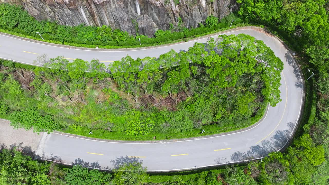 鸟瞰弯弯曲曲的柏油路和山上绿色的森林景观视频素材