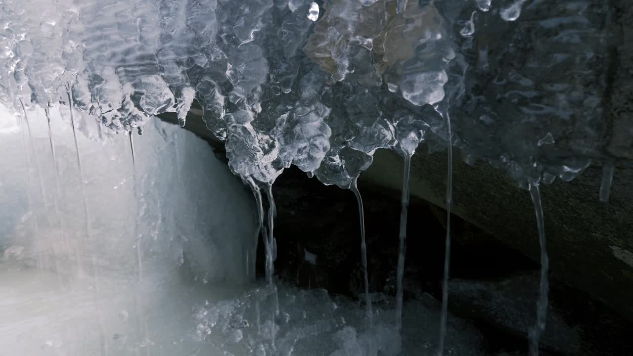 美丽透明的冰柱悬挂在洞穴里，滴水视频素材