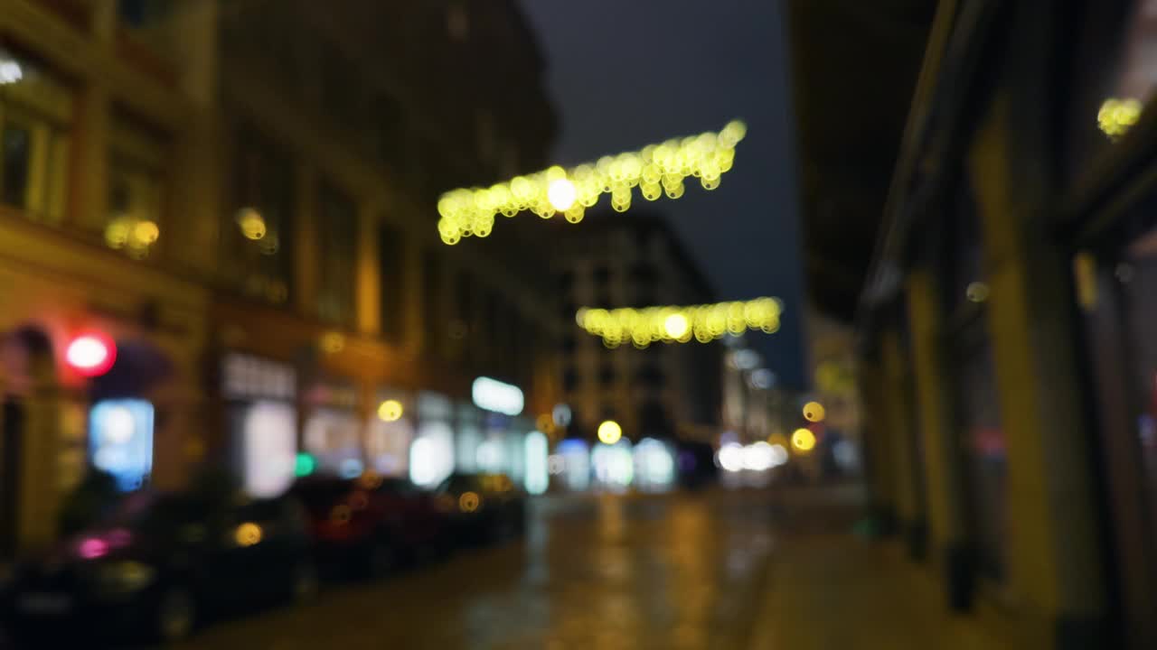 这是一张模糊的夜晚城市街道的照片，建筑物上悬挂着圣诞彩灯视频素材