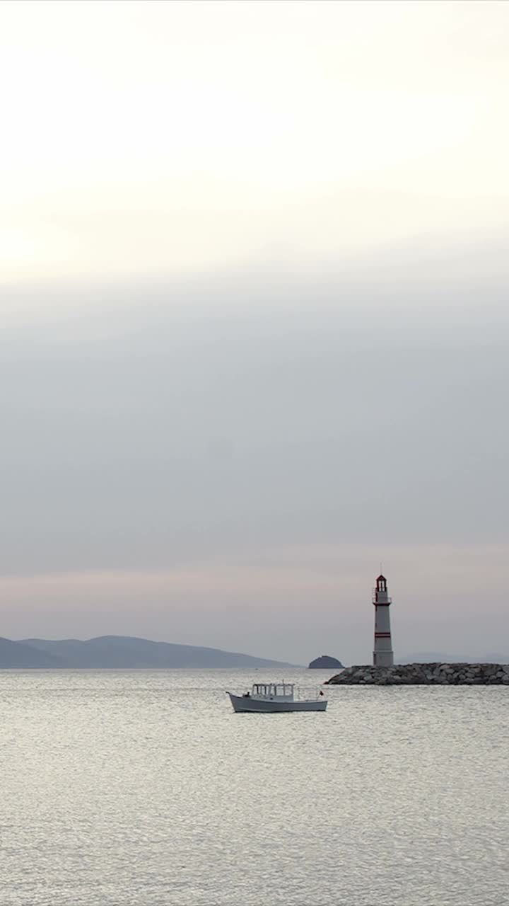 日落时的海景。海岸上的灯塔。海滨小镇Turgutreis和壮观的日落。社交媒体的垂直视频。视频下载