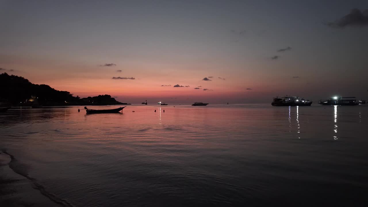 泰国涛岛宁静的海岸线上，漂浮着渔船和游船，沐浴在黄昏的红色天空中。旅行和度假的化身。视频素材