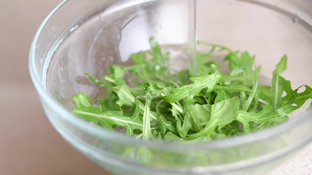 新鲜的芝麻菜叶子在水下清洗视频素材