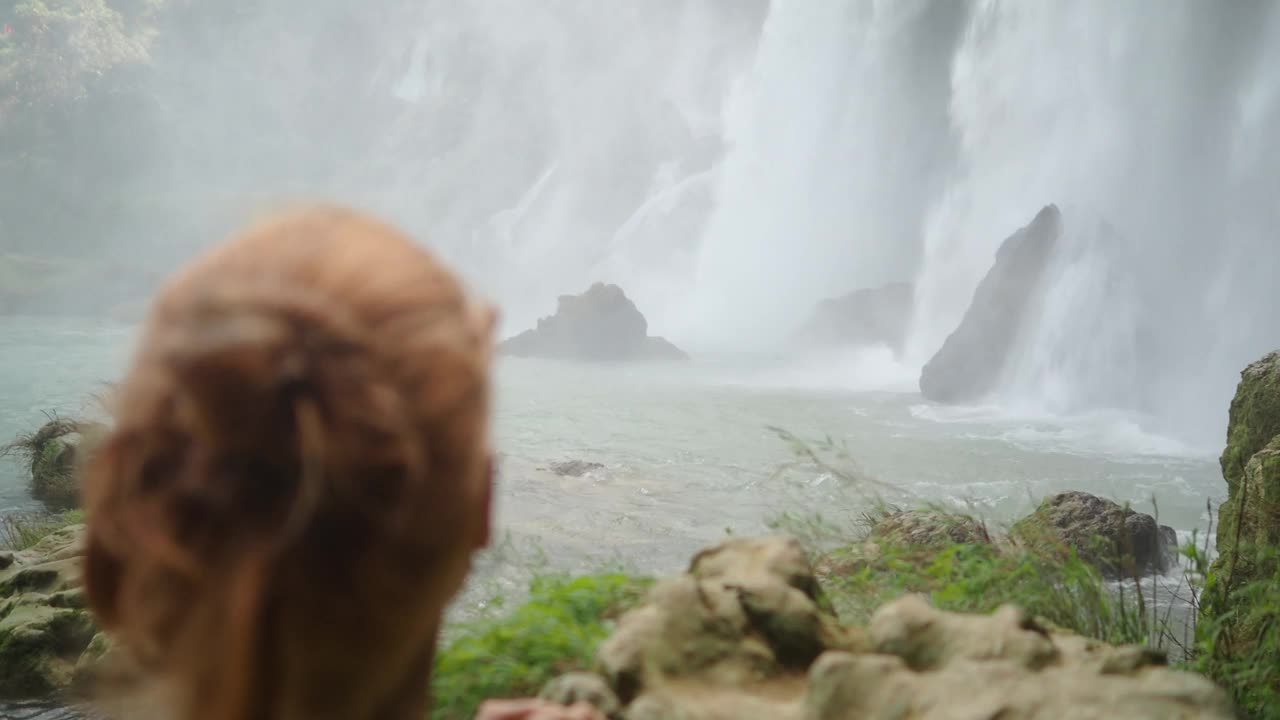 在一次旅行中，一位无法辨认的冒险女性在大自然中观察壮观的瀑布视频素材