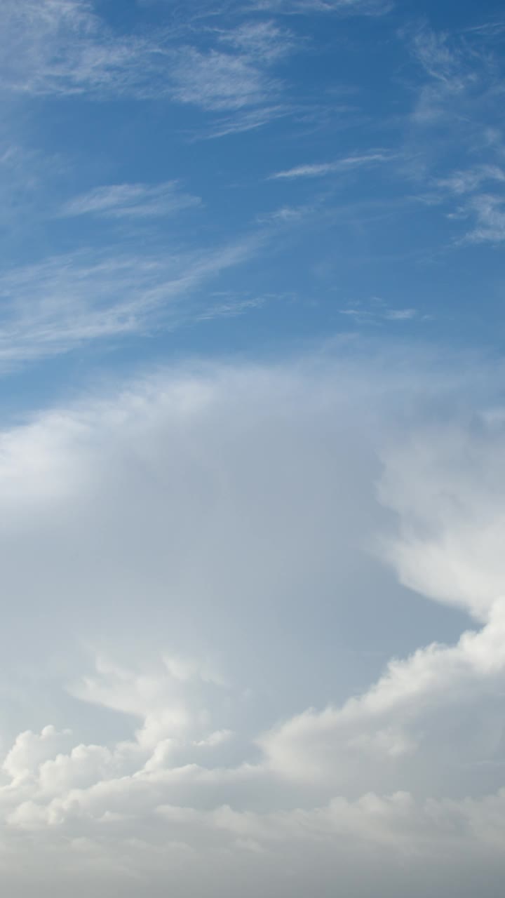 在炎热的天气里，当温暖潮湿的空气上升到很高的天空时，积雨云就会形成。从远处看，它们就像大山或高塔。多云的天空延时为背景。垂直视频素材