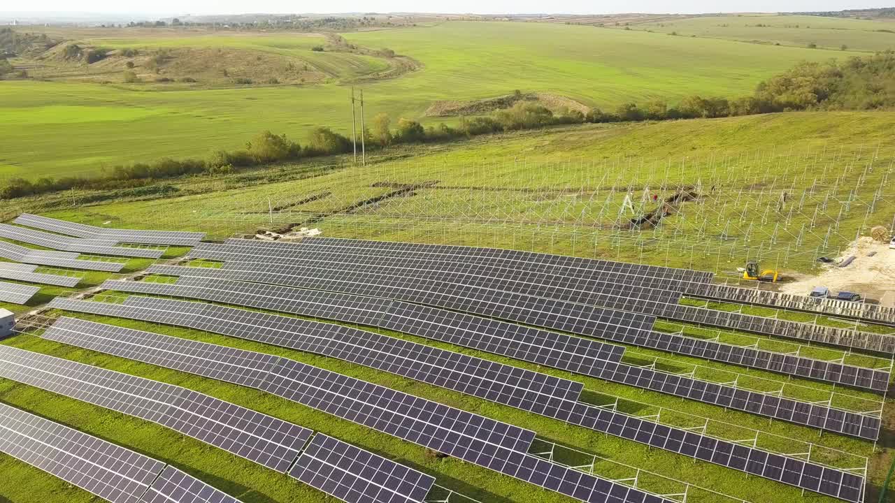 绿地上正在建设的太阳能发电厂鸟瞰图。组装用于生产清洁生态能源的电板视频素材