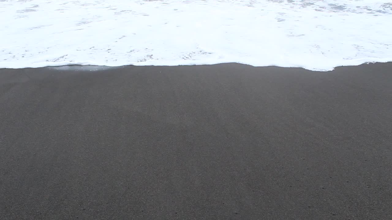 海滩上的浪花在沙滩上泛起泡沫视频素材