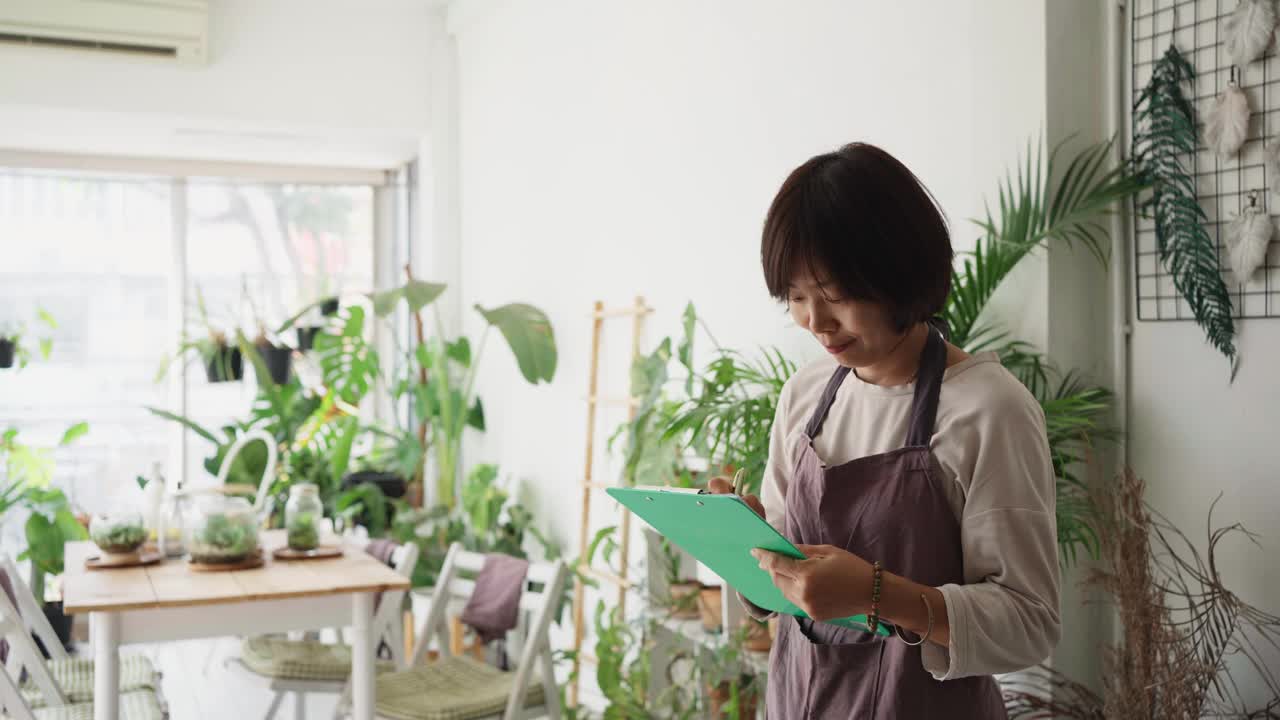 植物商店的女老板一边清点存货一边打电话视频素材