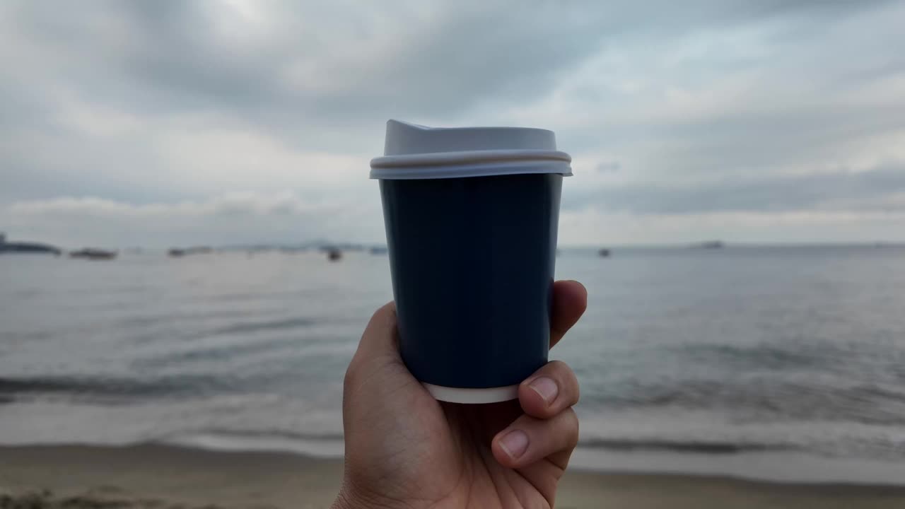 海边手持一次性咖啡杯。视频素材