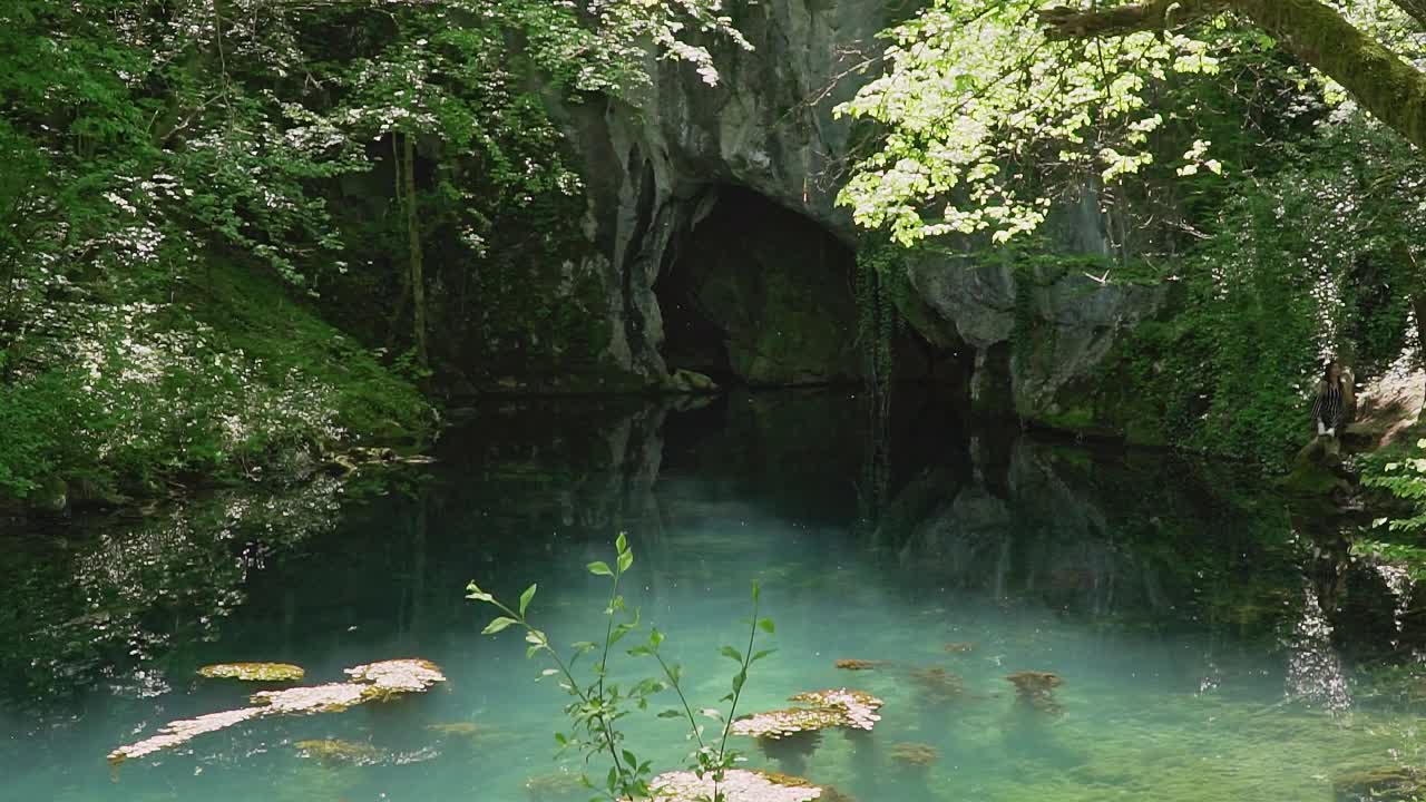 绿松石湖进入岩洞，周围环绕着绿色植被视频素材