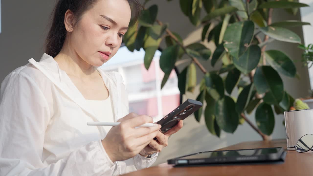 一个女人坐在桌子旁，手里拿着一块写字板和一支笔视频素材