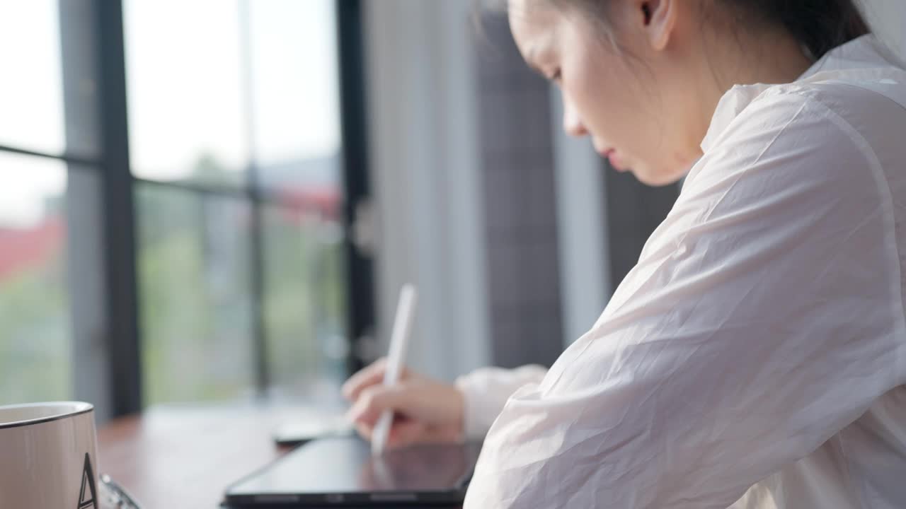 一个女人正坐在书桌前，在写字板上写字视频素材