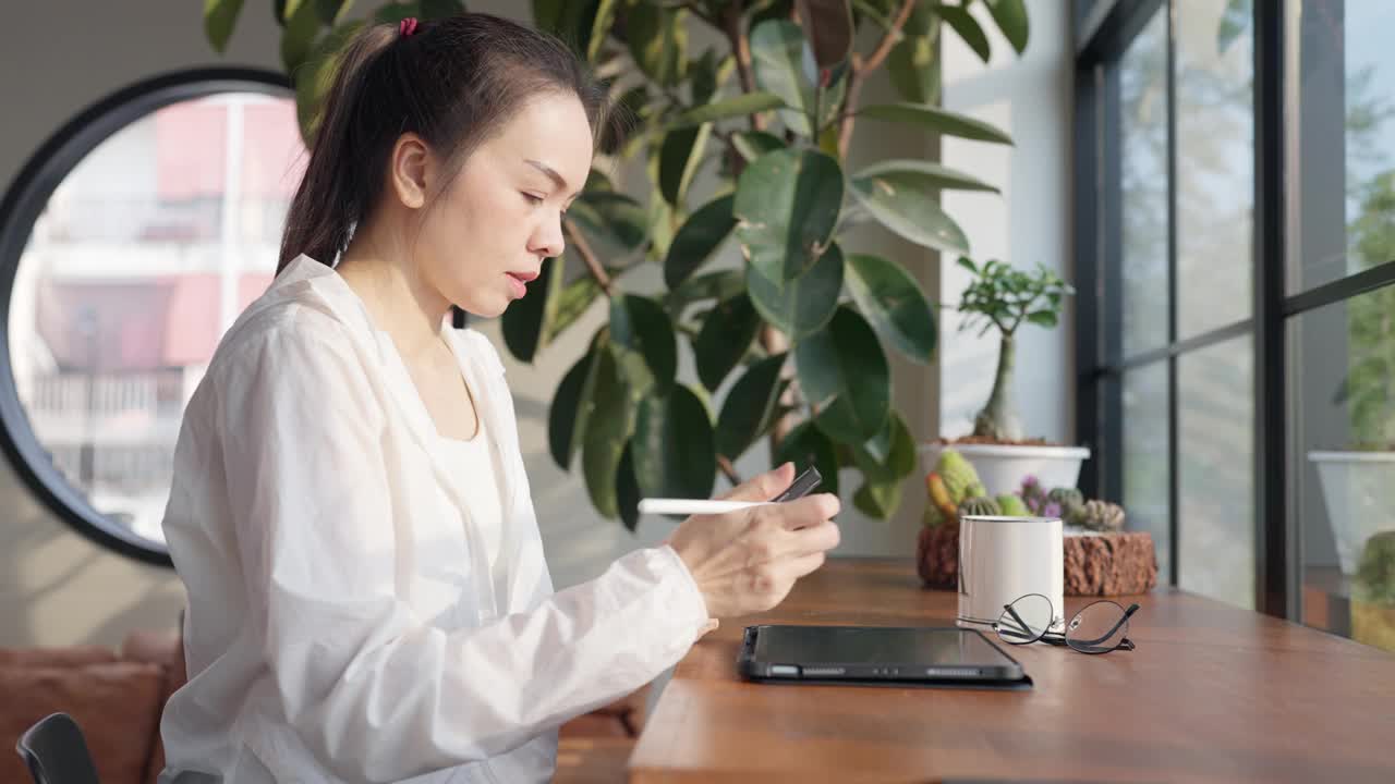 一个女人坐在桌子旁，手里拿着一块写字板和一支笔视频素材