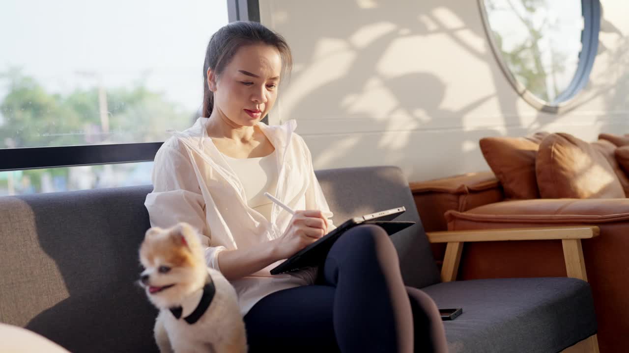 一个女人坐在沙发上，旁边有一只狗视频素材