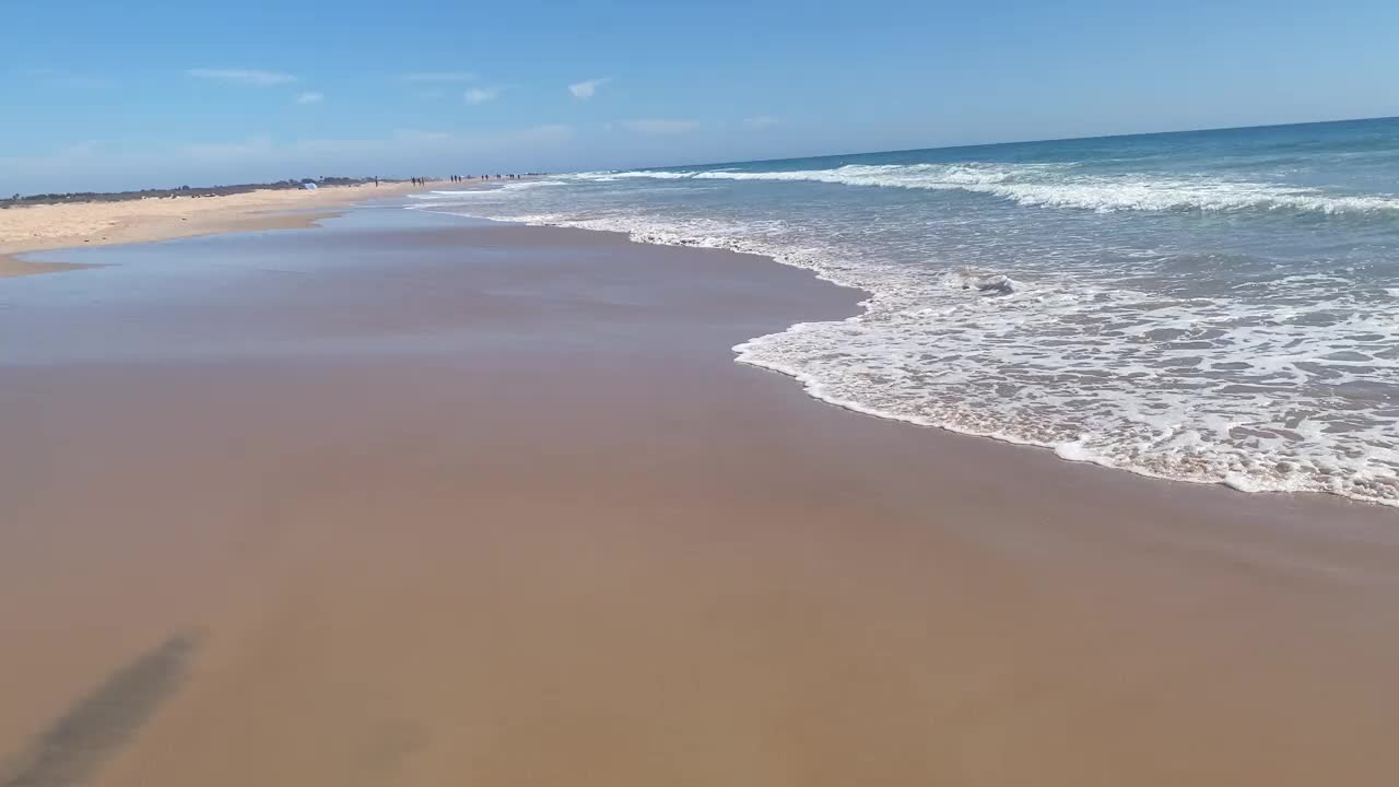 空旷的海滩，小波浪在海岸上破碎，海边的孤独:安静的海滩与平静的海水视频下载