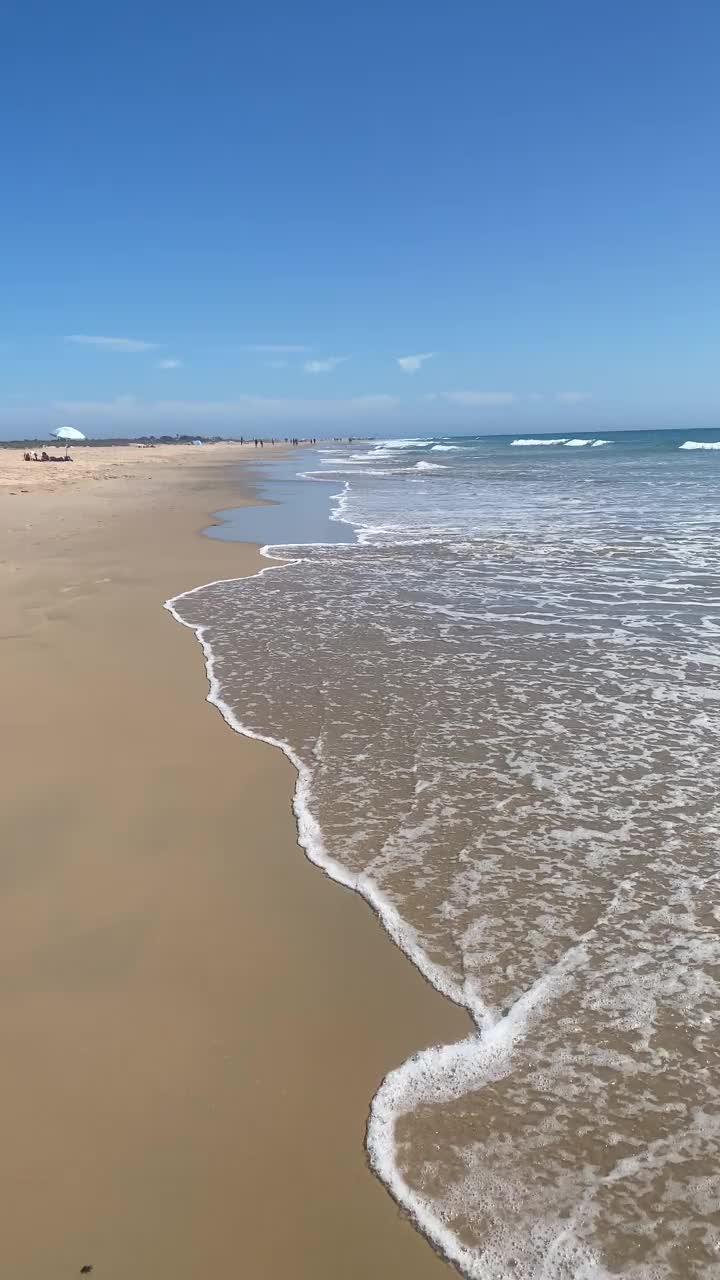 宁静的海岸:宁静的海滩景观与柔和的海浪。空旷的海滩上，小浪拍打着海岸视频下载