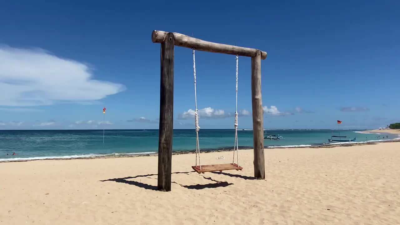 沙滩上的蓝天衬托着空秋千。视频下载