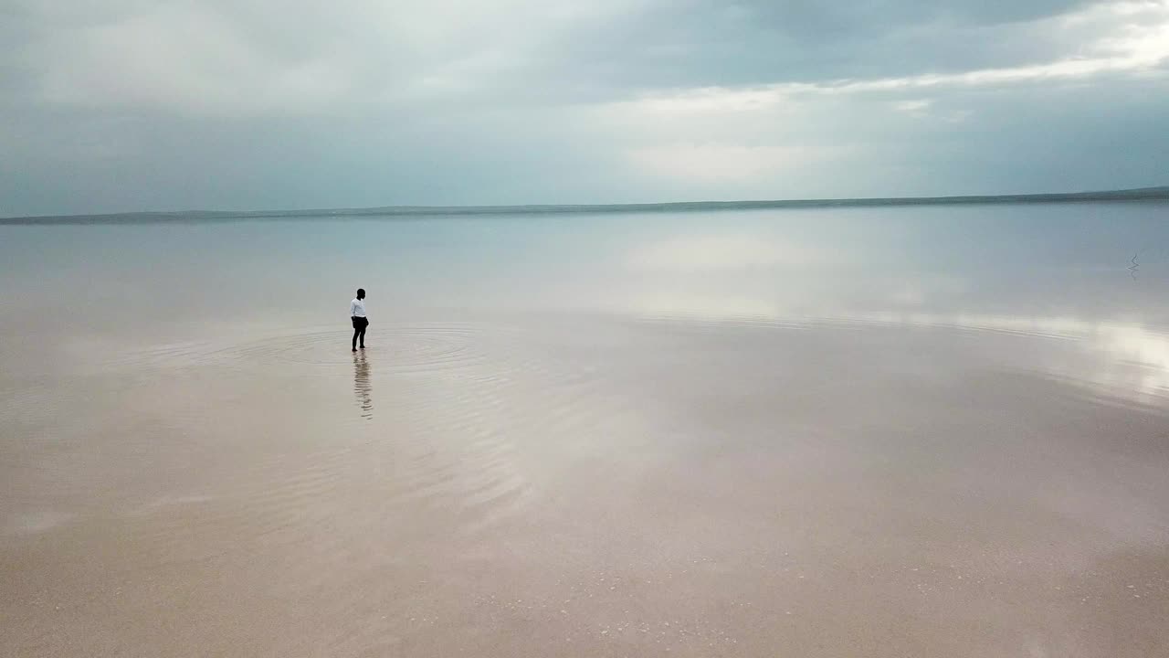 日落时分，一个人在热带海滩上跑步。一个人在海滩上奔跑的鸟瞰图视频下载