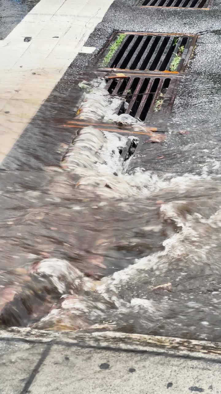 垂直视频显示，雨水涌入街道排水沟视频素材