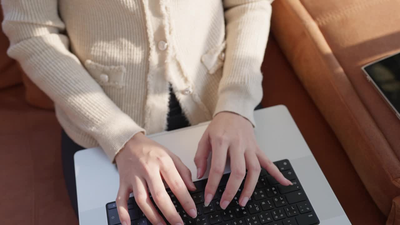一位穿着白色毛衣的女士正在笔记本电脑上打字视频素材