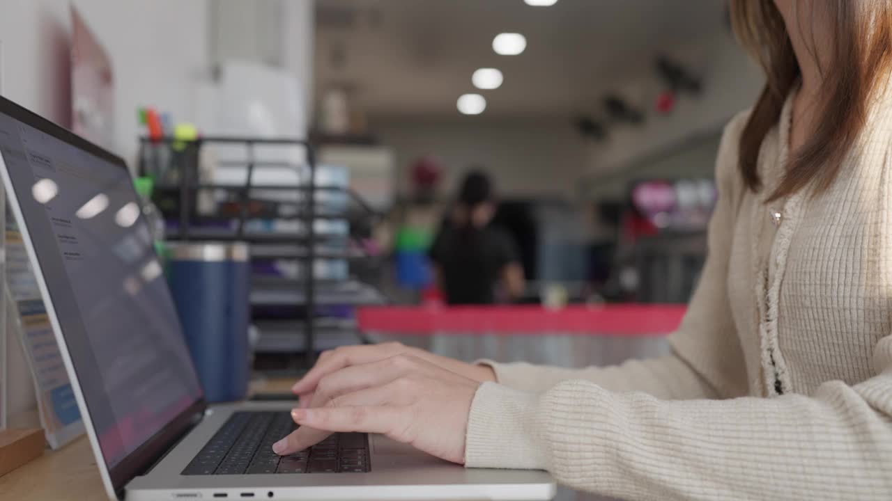 一位女士在商店里用笔记本电脑打字视频素材