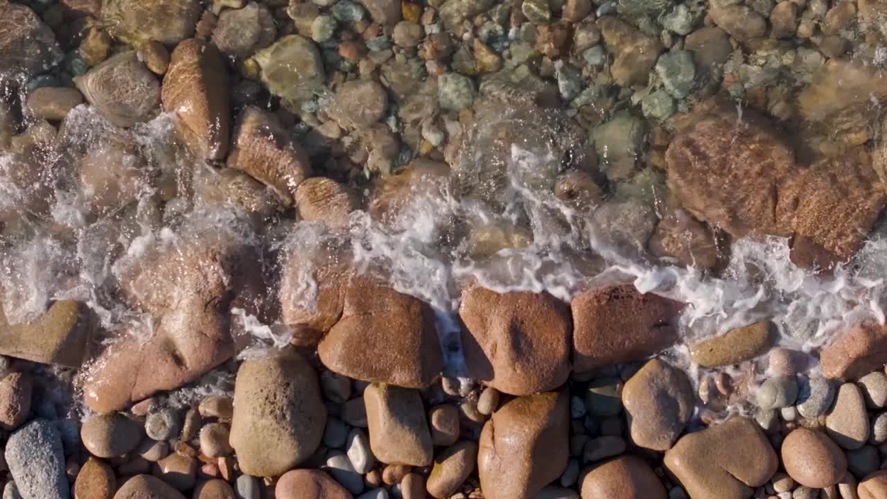 俯瞰日落时平静海浪的石质海滩视频素材