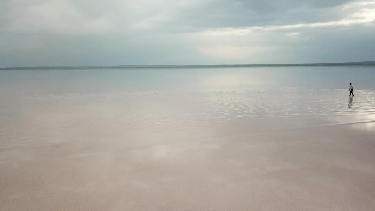 日落时分，一个人在热带海滩上跑步。一个人在海滩上奔跑的鸟瞰图视频素材