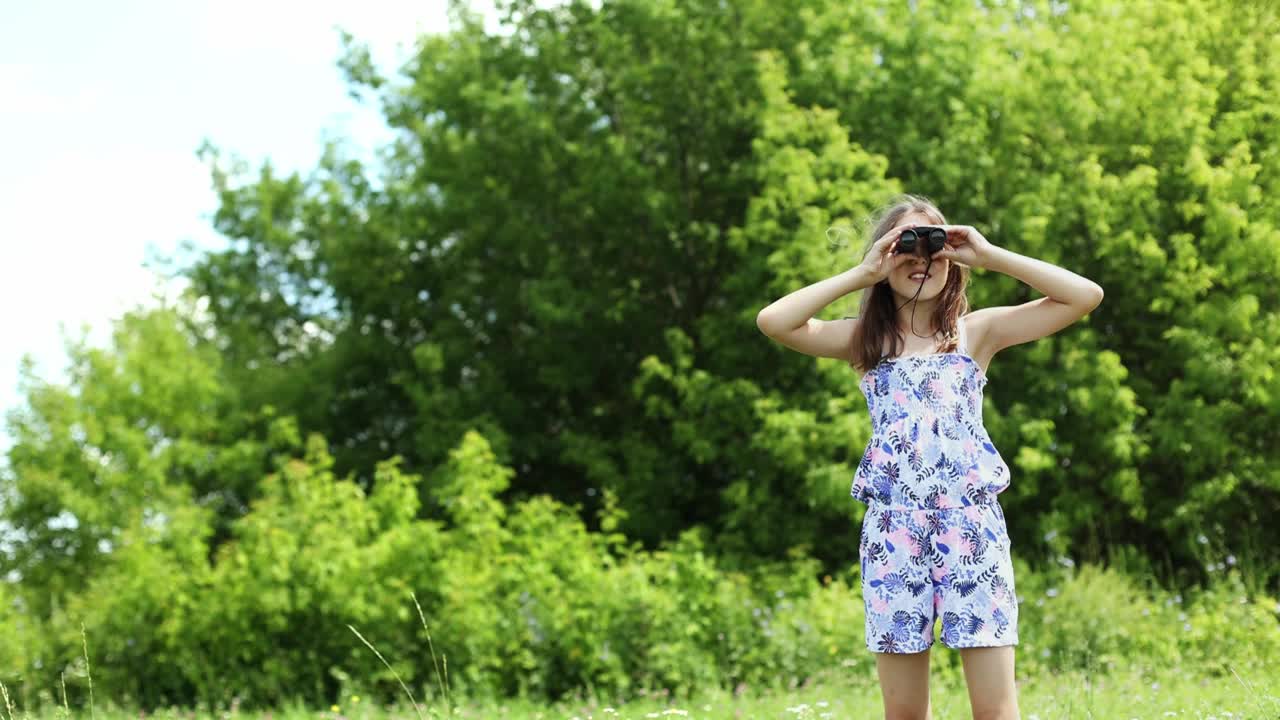 快乐的十几岁的女孩在夏天的户外通过双筒望远镜看和快乐地笑。视频素材