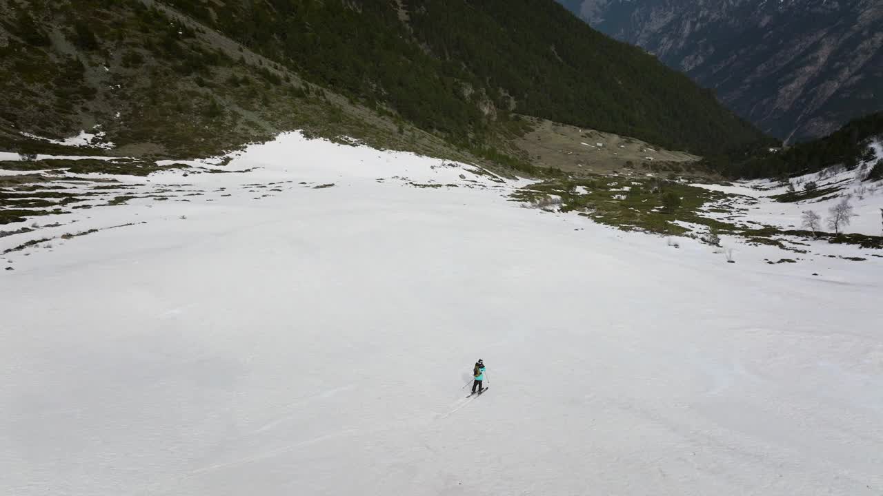 滑雪者在草地间的雪地上高速滑下峡谷视频素材