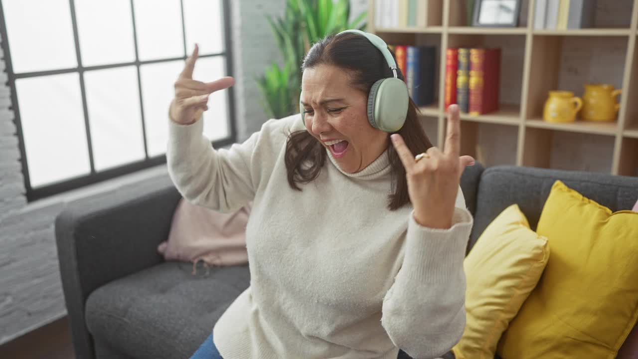 一个快乐的女人戴着耳机在家里跳舞，展示着舒适的室内环境，表达着幸福和悠闲。视频素材