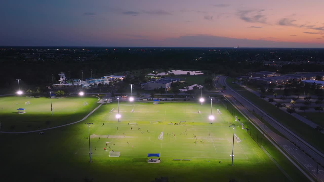 鸟瞰图的公共体育公园，人们从事足球比赛在草地体育场日落。积极的生活方式理念视频素材
