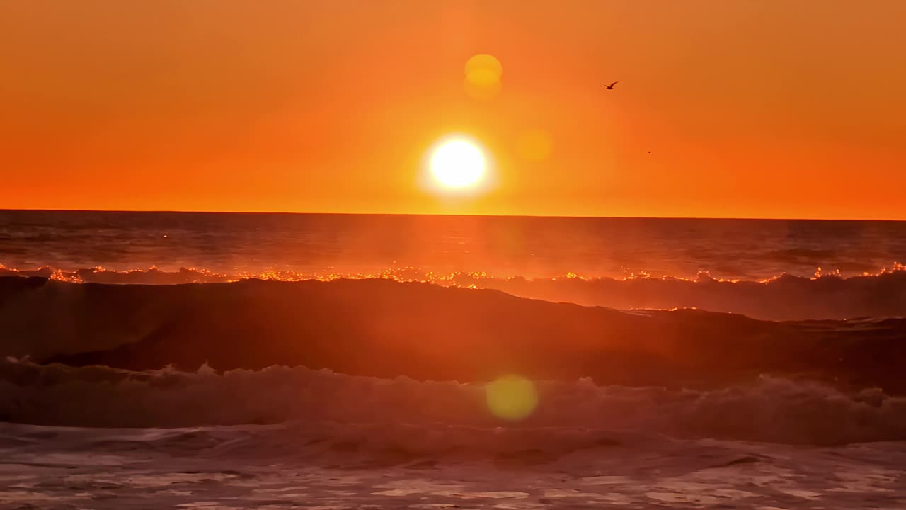 在宁静的海滩上，红色夕阳下的慢动作海浪视频素材