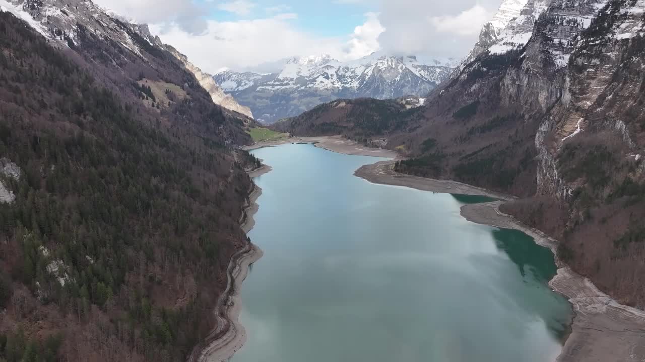 空中视角捕捉到瑞士格拉鲁斯的Klöntalersee，在高耸的Vorderglärnisch山和白雪皑皑的山峰之间，瑞士阿尔卑斯山的迷人之美。视频素材