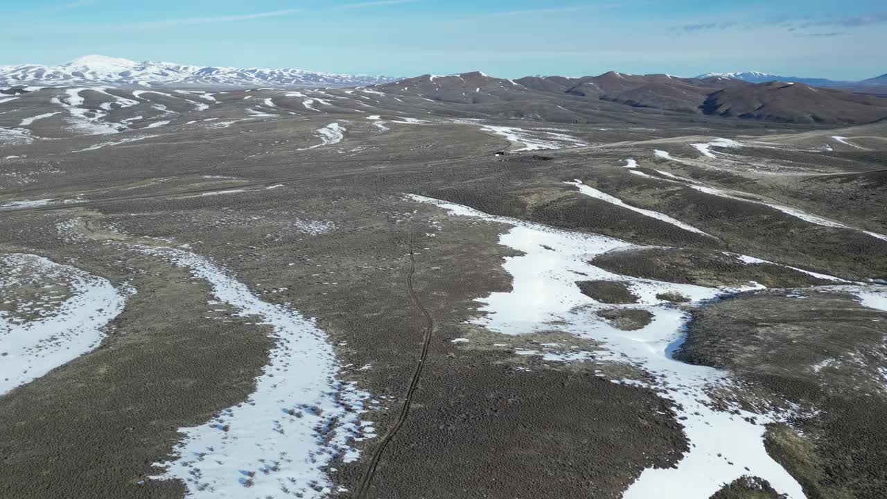 航拍的一个狭窄的道路通过广阔的滚动土地与雪坡在内华达州，美国视频素材