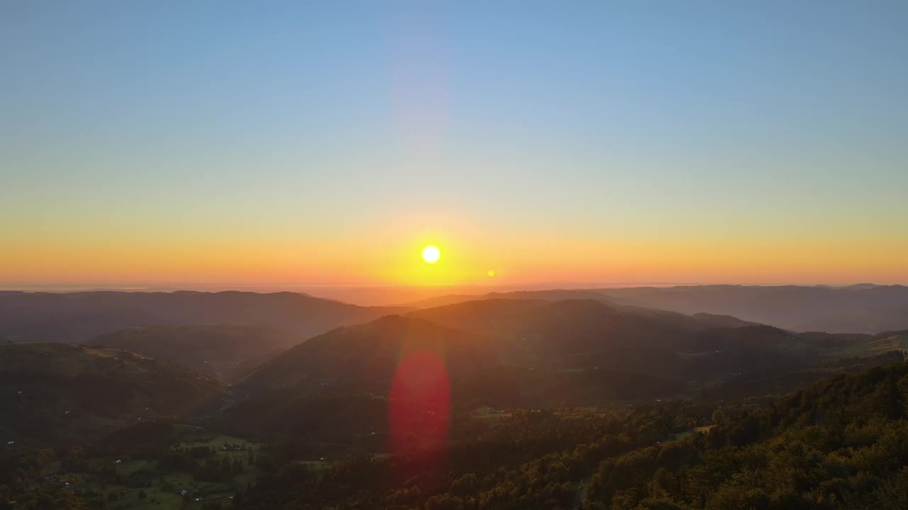 黑暗的松林被明亮的夕阳照亮。鸟瞰山野中五彩缤纷的日落。美丽的自然景观视频素材