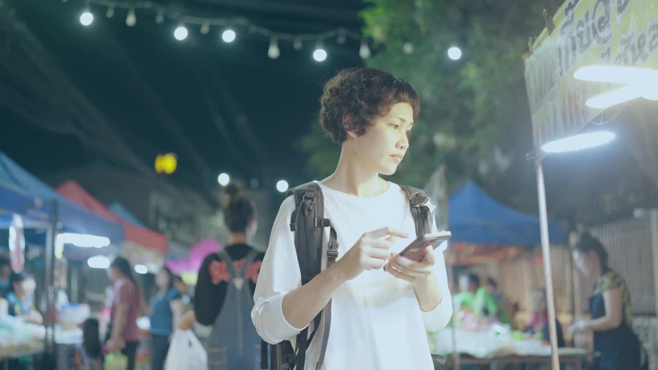 一个女人在拥挤的市场里看她的手机视频素材