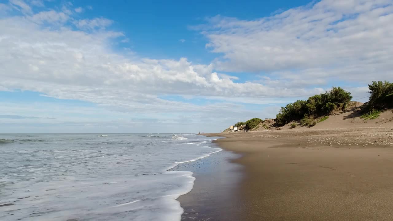 宁静的夏日救生员的房子，温柔的海浪，和遥远的人物在一个宁静的海滩视频素材