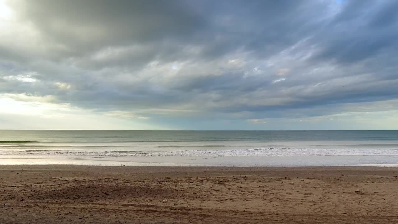 宁静的夏日，暴风雨的天空，宁静而孤独的海滩上温柔的海浪。视频素材