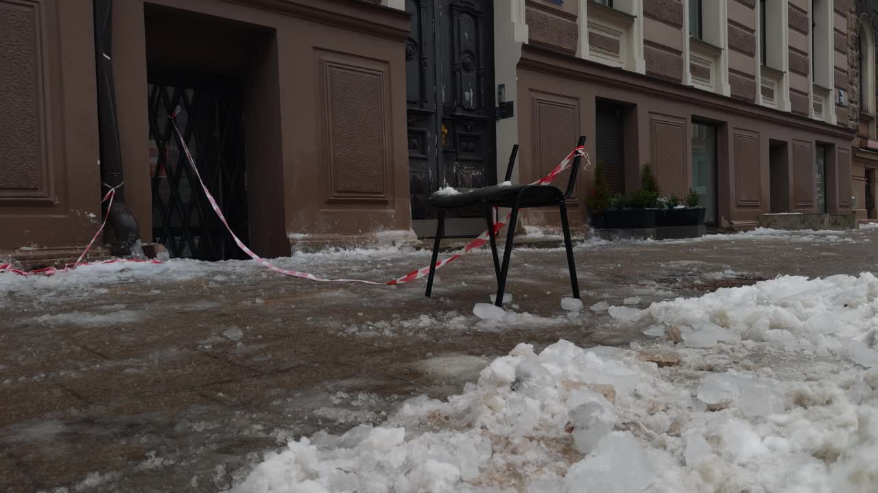 人行道上的一幢建筑物外的雪地里放着一把椅子视频素材