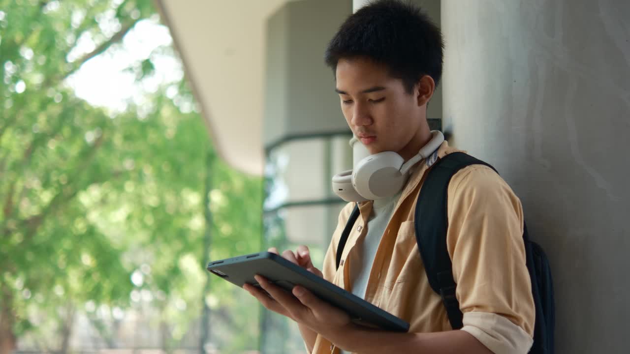 专注的学生在学校走廊上玩平板电脑视频素材