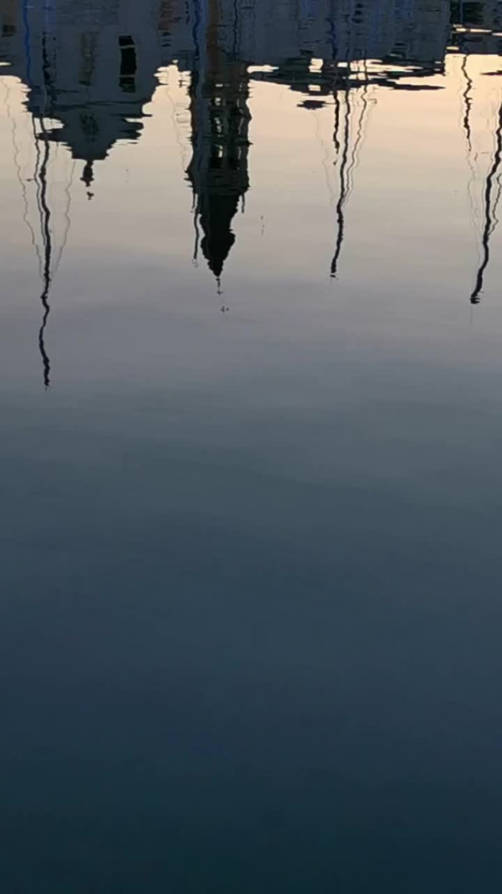 清晨，游艇的桅杆在水中倒映，停泊在风景如画的码头上。垂直视频视频素材