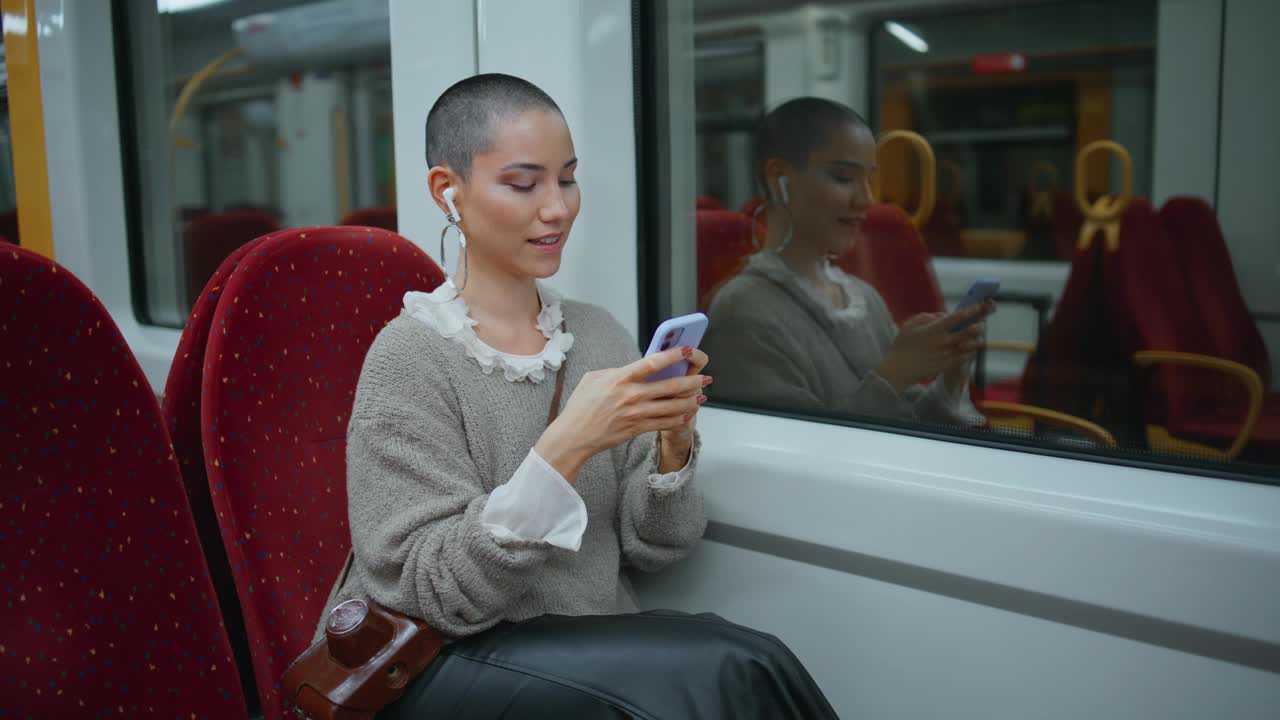 女孩旅行者短信智能手机坐在现代火车。短发女人发短信视频素材