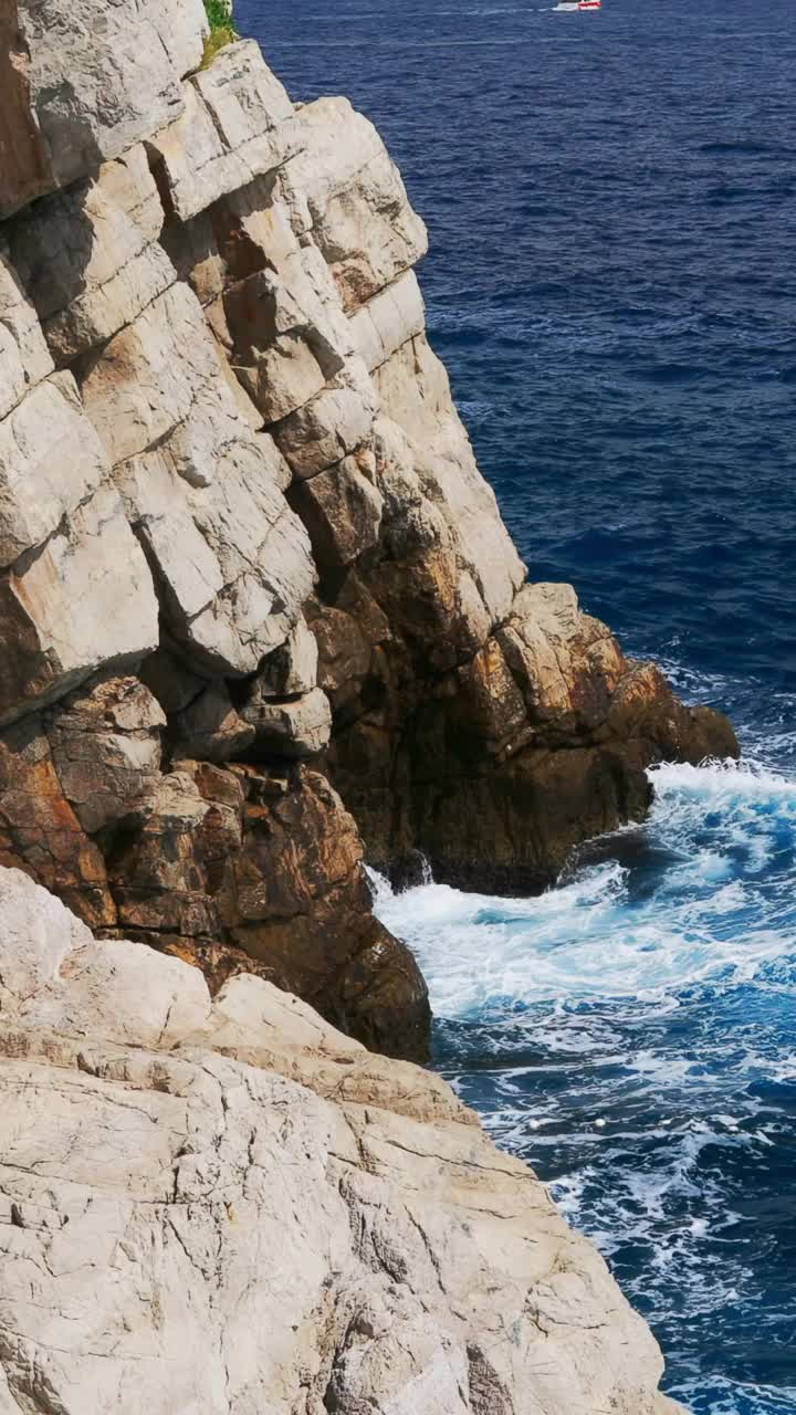 在一个阳光明媚的夏日，亚得里亚海的海浪冲击着岩石嶙峋的海岸线。垂直视频视频素材