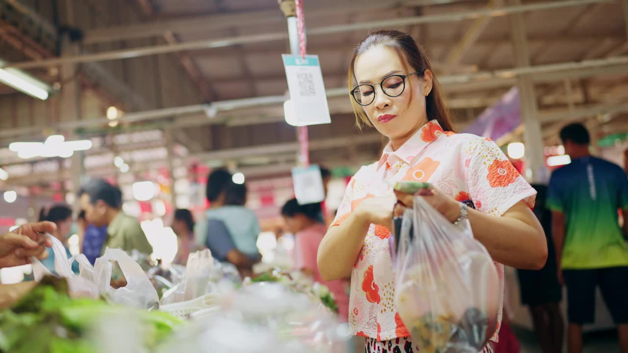 一个女人在市场购物，看着一袋农产品视频素材