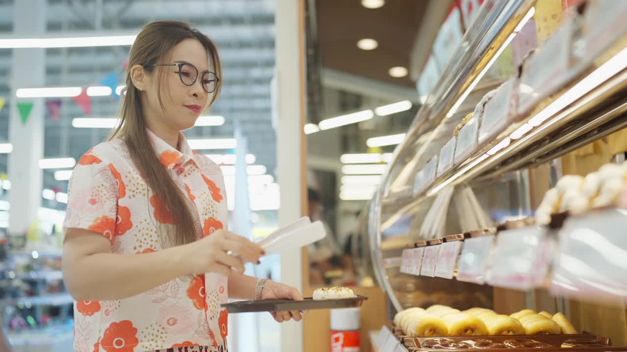 一位穿着印花衬衫的女士正在商店里买食物视频素材