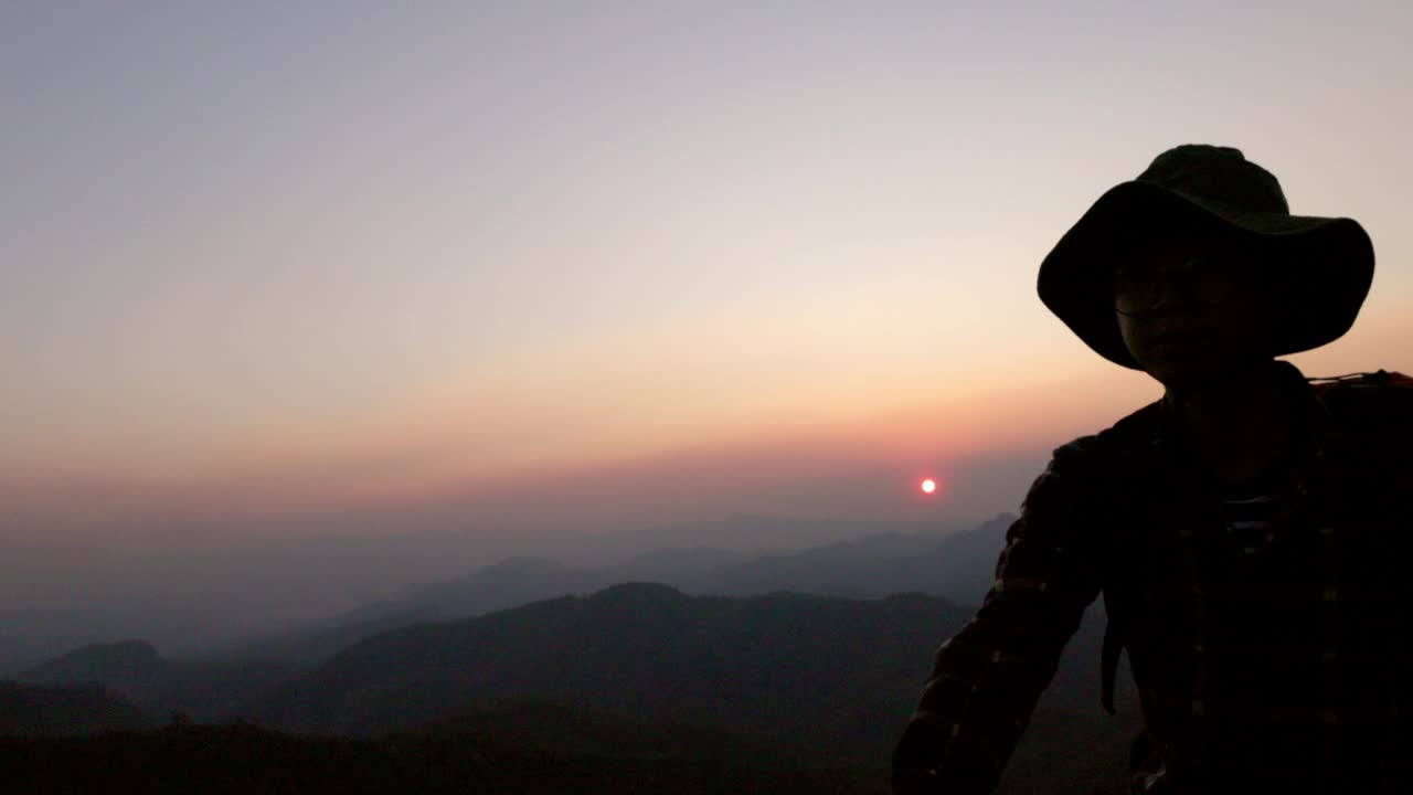 徒步旅行者爬上山崖的剪影。攀爬团队在夕阳下互相帮助。帮助和团队合作的概念。视频素材