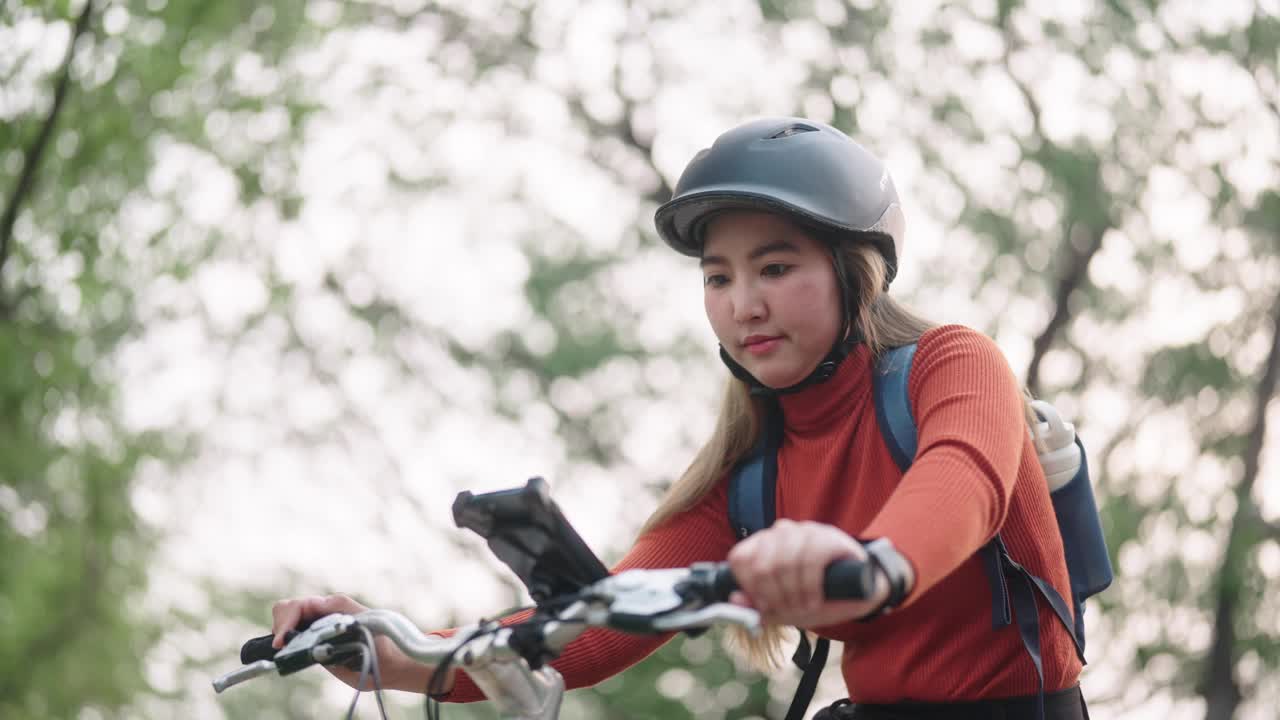 女子骑自行车旅行时使用智能手机。视频下载