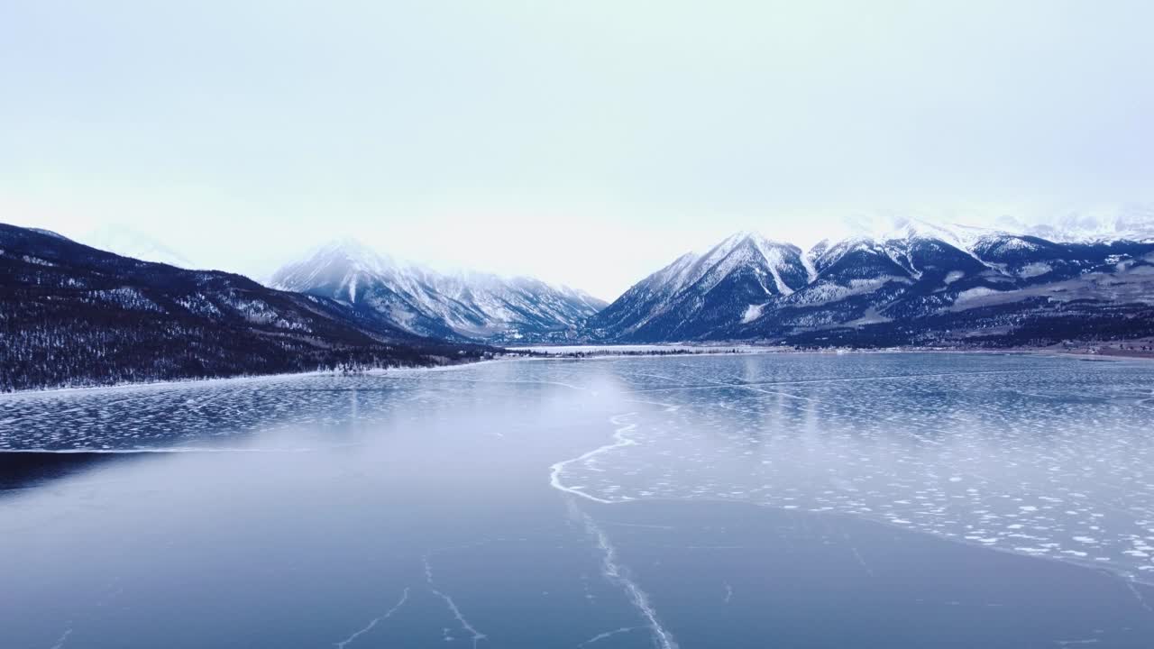 冰封的湖泊，背景是白雪皑皑的山脉和多云的天空，多莉视频素材